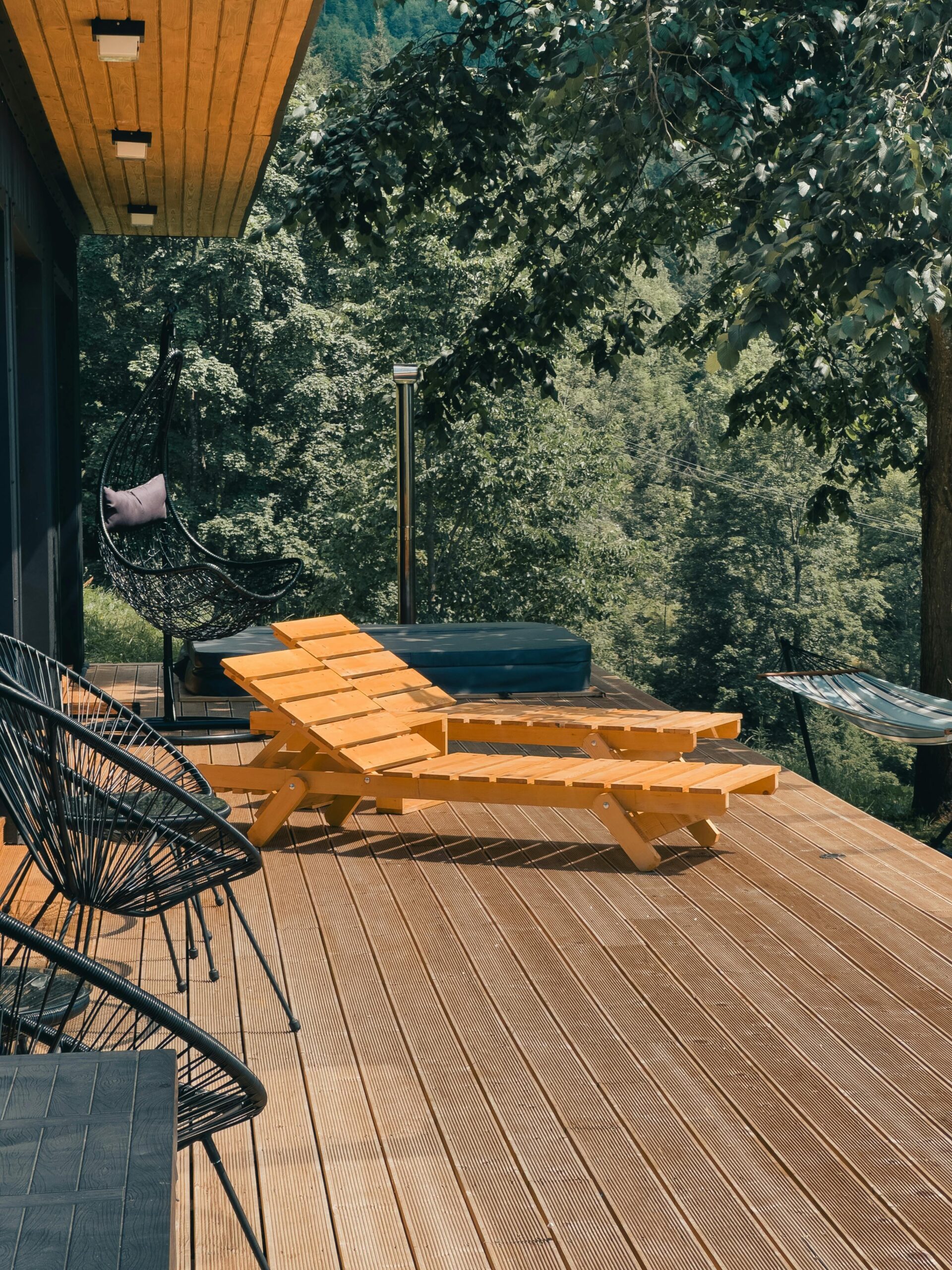 Wooden deck with lounge chairs surrounded by lush greenery, perfect for relaxation.